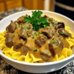 For a tasty beef stroganoff, you'll need: - 1.5 pounds beef chuck roast, cut into bite-sized pieces - 1 onion, finely chopped - 3 cloves garlic, minced - 8 ounces mushrooms, sliced - 2 cups beef broth - 1 tablespoon Worcestershire sauce - 1 teaspoon dried thyme - Salt and pepper to taste - 1 cup sour cream These ingredients create a rich and hearty dish. The beef chuck roast gives a tender texture. The onion and garlic add a sweet flavor, while mushrooms bring an earthy taste. Worcestershire sauce adds depth, and thyme gives a hint of freshness. For the egg noodles, gather: - 12 ounces egg noodles Egg noodles cook quickly and soak up the rich sauce well. They provide a soft base for the beef stroganoff and create a cozy meal. If you want a thicker sauce, consider using: - 2 tablespoons cornstarch (optional, for thickening) Using cornstarch helps to create a creamy and satisfying texture. You can mix it with a bit of water before adding it to the sauce. This step is optional, but it can enhance the dish's richness. Start by cutting the beef chuck roast into small, bite-sized pieces. You want them easy to eat. Next, finely chop the onion and mince the garlic cloves. Slice the mushrooms into thin pieces. These steps make the dish more flavorful. Now, in a large bowl, season the beef with salt and pepper. This adds taste to the meat. You can also prepare the beef broth and Worcestershire sauce now. Measure them out so you can add them quickly later. Begin layering in your crockpot. Place the chopped onion, minced garlic, and sliced mushrooms at the bottom. This forms a tasty base. Next, add the seasoned beef on top of the veggies. Pour the beef broth over everything. Add the Worcestershire sauce and sprinkle dried thyme on top. This combination will create a rich flavor as it cooks. Make sure all the ingredients are evenly distributed. Cover the crockpot with its lid. Cook on low for 6 to 8 hours or on high for 4 hours. The beef should be tender when done. If you want a thicker sauce, mix cornstarch with water about 30 minutes before serving. Stir it into the mixture to thicken. About 30 minutes before serving, mix in the sour cream. This adds creaminess to the dish. During the last 10 to 15 minutes, cook the egg noodles according to the package instructions. Drain and set them aside. When everything is ready, combine the noodles with the beef stroganoff or serve the sauce on top. Don’t forget to garnish with chopped parsley for a fresh touch! To get tender beef in your stroganoff, you need the right cut. I use beef chuck roast. It cooks well low and slow. Cut it into small, bite-sized pieces. Season with salt and pepper before cooking. This helps to enhance the beef’s flavor. Cook it for six to eight hours on low. This long cook time makes the beef melt in your mouth. The sauce should be creamy and rich. To get this, add sour cream about 30 minutes before serving. Stir it in well to mix. If you like a thicker sauce, use cornstarch. Mix it with a little water and add it in the last 30 minutes of cooking. This will make your sauce nice and thick. It coats the noodles perfectly. Egg noodles are a great match for beef stroganoff. Cook them just before serving. Drain them and toss them with the sauce. You can also serve the sauce on top of the noodles. For a nice touch, sprinkle fresh parsley on top. It adds color and flavor. Enjoy this cozy meal with a side salad or some crusty bread. {{image_2}} You can swap beef for other meats. Chicken works great in stroganoff. Just use boneless chicken thighs or breasts. Cook them the same way as beef. Pork is another tasty option. Use pork shoulder for a rich flavor. You can even try turkey for a lighter dish. Each protein gives a unique twist to the classic recipe. If you want a meatless meal, there are many tasty swaps. Try using mushrooms as the main ingredient. Portobello mushrooms have a great texture and flavor. You can also add lentils or chickpeas for protein. Use vegetable broth instead of beef broth. This keeps the dish hearty and satisfying. Don’t forget to stir in some sour cream or plain yogurt for creaminess. Egg noodles are a classic, but other options exist. You can use wide pasta like fettuccine or tagliatelle. They hold the sauce well and taste great. If you want a gluten-free option, try rice noodles or zucchini noodles. They add a fresh touch and are fun to eat. Choose your noodles based on your taste and dietary needs. Store leftover beef stroganoff in an airtight container. It keeps well in the fridge for 3-4 days. Make sure to let it cool to room temperature before sealing. This helps prevent moisture build-up. If you need more time, consider freezing it. Reheat beef stroganoff on the stove for best results. Use low heat and stir often. You can also microwave it in short bursts. Just cover the bowl to keep it moist. Add a splash of beef broth if it seems dry. To freeze beef stroganoff, let it cool first. Portion it into freezer-safe containers. Label each container with the date. It will last up to 3 months in the freezer. Thaw it overnight in the fridge before reheating. This keeps the flavors fresh and tasty. Yes, you can make this beef stroganoff ahead of time. Just follow the recipe as usual. Once you finish cooking, let it cool. Then, store it in the fridge. This dish tastes even better the next day as the flavors blend. Just reheat it on the stove or in the microwave before serving. If you need a substitute for sour cream, try Greek yogurt. It has a similar texture and tangy flavor. You can also use cream cheese or buttermilk. Adjust the amount to your liking. Each will give a nice creaminess to the dish. To make this beef stroganoff gluten-free, use gluten-free egg noodles. Check the labels to ensure they are truly gluten-free. For thickening, replace cornstarch with a gluten-free flour mix. The rest of the recipe stays the same, and you will still enjoy a cozy meal! Beef Stroganoff is a tasty dish made with beef and creamy sauce over noodles. You learned about the main ingredients, how to prep them, and cooking tips for the best flavor. I shared variations, storage tips, and answers to common questions. Enjoy experimenting with this dish and find what you love. Cooking can be fun and simple. Try new things, and make it your own! Your kitchen is a place of joy.