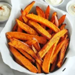 - 2 large sweet potatoes - 2 tablespoons olive oil - 1 teaspoon garlic powder - 1 teaspoon paprika - ½ teaspoon cayenne pepper (optional) - Salt and pepper to taste - 1 tablespoon cornstarch For this recipe, you need to gather all the right ingredients. Start with two large sweet potatoes. Look for firm ones with vibrant skin. Next, you will need two tablespoons of olive oil. This will help your fries get crispy. Add one teaspoon of garlic powder for flavor. Paprika will give your fries a nice color and taste, so include one teaspoon of it too. If you want some heat, add half a teaspoon of cayenne pepper. This step is optional, so feel free to skip it if you prefer mild fries. Season with salt and pepper to taste. Finally, get one tablespoon of cornstarch. This ingredient is key to achieving that perfect crunch on your fries. These ingredients set the stage for a delicious snack or side dish. They come together to create a tasty and crispy bite that you will love! Start with two large sweet potatoes. Peel them, then cut them into thin strips. Aim for about ¼ inch thick. Keeping the fries the same size helps them cook evenly. If they are not uniform, some will be soft while others will burn. After cutting, soak the fries in cold water for 30 minutes. This step is key. Soaking removes extra starch, which helps the fries get crispy. After soaking, drain the fries. Dry them well with a kitchen towel. Wet fries will not crisp up nicely. Now it’s time to season the fries. In a large bowl, toss the dry, cut fries with olive oil. Use about 2 tablespoons. Add 1 teaspoon of garlic powder, 1 teaspoon of paprika, and salt and pepper to taste. If you want heat, add ½ teaspoon of cayenne pepper. Mix until all fries are coated. Next, sprinkle 1 tablespoon of cornstarch over the fries. Toss again to coat. The cornstarch is vital for that crunchy texture. Before cooking, preheat your air fryer to 400°F (200°C). This usually takes about 5 minutes. Once preheated, place the fries in the basket in a single layer. If your air fryer is small, you may need to cook in batches. Cook the fries for 15-20 minutes. Shake the basket halfway through for even cooking. Look for golden brown color and crispiness. If you want them extra crispy, add 2-3 more minutes to the cooking time. To get the best crispiness in your sweet potato fries, drying them is key. After soaking your fries, make sure to pat them dry with a kitchen towel. The less moisture on the fries, the better they crisp up in the air fryer. You can also adjust cooking times to fit your taste. If you like your fries softer, cook them for 15 minutes. For extra crunch, add a few more minutes. Just keep an eye on them so they don’t burn. When it comes to dips, I love spicy mayo and garlic aioli. They add a nice kick and flavor to your fries. You can also try ketchup or a tangy yogurt dip for something different. For presentation, serve your fries in a stylish basket lined with parchment paper. This makes them look fancy and keeps them warm. Adding a small bowl of dips on the side makes it fun for everyone. {{image_2}} You can change up the flavor of your sweet potato fries with different spices. Here are some fun ideas: - Cumin: Adds a warm, earthy taste. - Chili powder: Gives a nice kick to your fries. - Italian seasoning: A blend of herbs for a classic touch. You can also add fresh herbs for extra flavor. Try: - Rosemary: Chopped finely, it adds a great aroma. - Thyme: Gives a nice herbal note. - Parsley: Brightens up the dish with freshness. While sweet potatoes are delicious, don’t stop there! You can try other vegetables in the air fryer. Here are a few options: - Carrots: Cut them into sticks for a sweet crunch. - Zucchini: Slice them into fries for a light option. - Beets: Use them for a colorful and earthy twist. All these veggies air-fry well and can be seasoned just like sweet potatoes. Air frying is a healthy way to cook fries. It uses hot air to create a crispy texture without much oil. Here’s how it compares to traditional frying: - Less oil: Air frying uses little to no oil, making it healthier. - Crispier texture: The hot air circulates around the food, creating a great crunch. - Faster cooking: Air fryers cook food quicker than deep frying. Overall, air frying gives you tasty fries while keeping things lighter. To keep your sweet potato fries fresh, store them in an airtight container. Let the fries cool completely before putting them away. If you have leftovers, use parchment paper to separate layers. This helps prevent them from getting soggy. You can keep them in the fridge for up to three days. To reheat your fries and keep them crispy, use the air fryer again. Preheat it to 375°F (190°C). Place the fries in a single layer and heat for about 5-7 minutes. This method helps restore their crunch. You can also use an oven at the same temperature, but the air fryer works best for keeping that crispy texture. Avoid using the microwave, as it can make them soft and mushy. To make sweet potato fries crispier, you can follow a few key tips: - Soak the fries: Soaking in water for at least 30 minutes helps remove starch. - Dry them well: After soaking, dry the fries thoroughly with a towel. This step is crucial. - Use cornstarch: Tossing the fries with cornstarch before air frying adds extra crunch. - Don’t overcrowd: Place fries in a single layer in the air fryer. This helps them cook evenly. With these adjustments, you can achieve that perfect crispy texture you desire. Yes, you can prepare sweet potato fries ahead of time. Here’s how: - Prep ahead: Cut and soak the fries earlier in the day. Store them in water in the fridge. - Dry before frying: When you are ready to cook, drain and dry the fries well. - Store cooked fries: If you have leftovers, let them cool fully. Place them in an airtight container in the fridge. This way, you can enjoy your crispy fries later without losing their great taste. The ideal temperature for air frying sweet potatoes is 400°F (200°C). Here’s why this temperature works well: - Crispiness: Cooking at this temperature helps achieve a crispy outer layer. - Even cooking: It ensures that the fries cook through without burning. - Quick cooking: This temperature allows the fries to cook in just 15-20 minutes. Keep an eye on them, and shake the basket halfway for the best results. Sweet potato fries are a tasty and healthy option. We covered ingredients, prep steps, and air frying tips. You learned how to achieve crispiness with the right techniques. Plus, we explored fun variations and best ways to store and reheat leftovers. Now you can enjoy make these fries and share them with others. With a few simple tweaks, you can make them your own. Just remember, practice makes perfect in the kitchen!